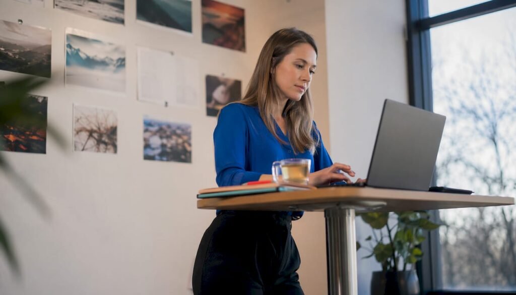 Eine Frau sitzt am Schreibtisch und arbeitet an der Gestaltung ihrer Webseite.