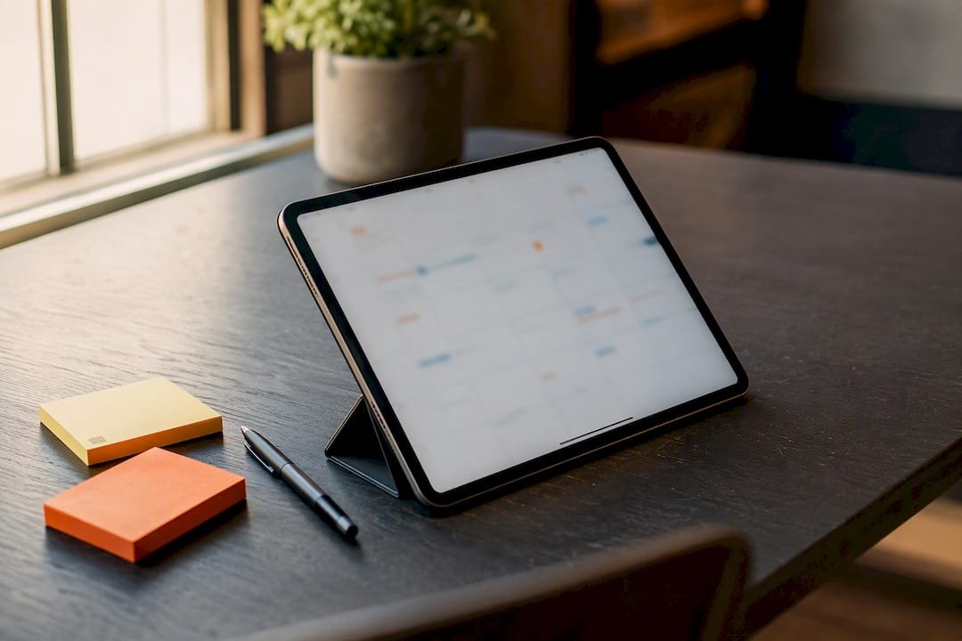 Ein Tablet zeigt den Redaktionsplan, daneben liegen handschriftliche Notizen.
